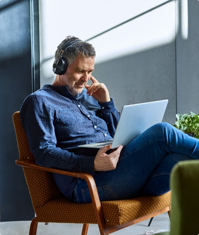 An Indiana man works on his computer with noise-cancelling headphones to protect his ears from hearing loss.