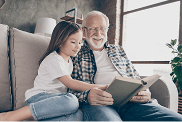 An older man with hearing trouble reading to his granddaughter in Elkhart Indiana 